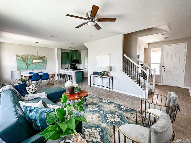 living room with hardwood / wood-style flooring, a textured ceiling, and ceiling fan