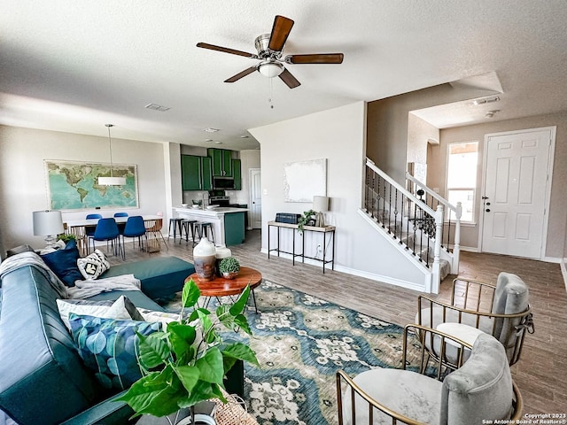 living room with ceiling fan, wood-type flooring, and a textured ceiling