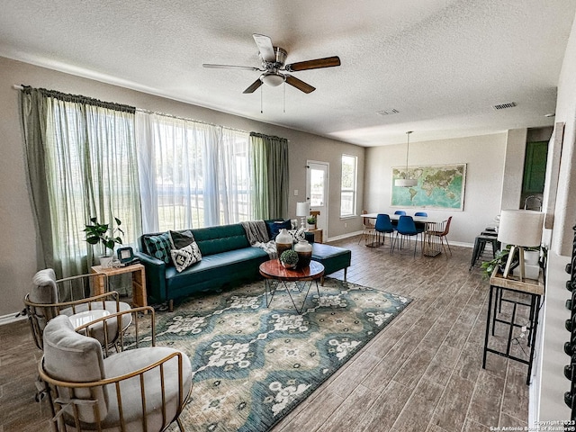 living room featuring ceiling fan, wood-type flooring, and a textured ceiling