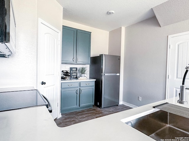 kitchen featuring stainless steel refrigerator, dark hardwood / wood-style floors, sink, and a textured ceiling