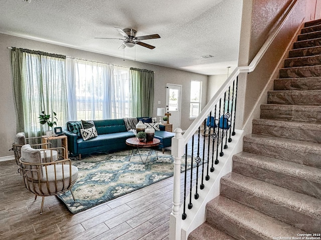 living room with a textured ceiling and ceiling fan