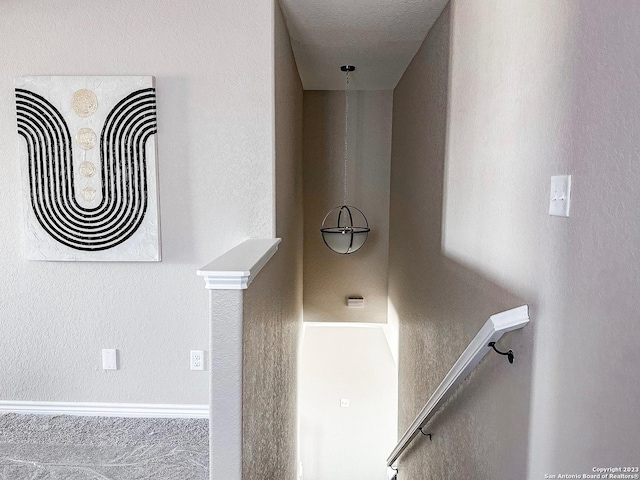 stairway featuring a textured ceiling