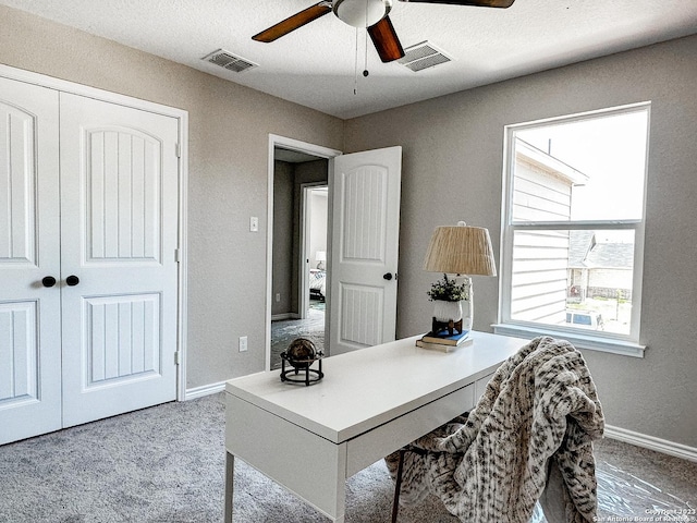 home office featuring light carpet, ceiling fan, and a textured ceiling