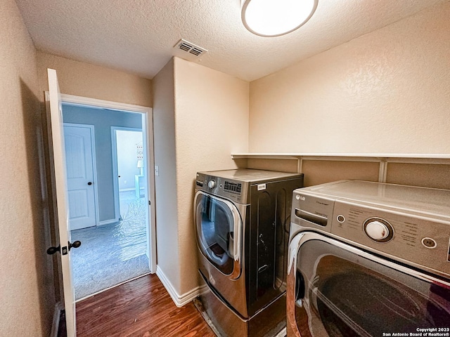 laundry room with separate washer and dryer, dark wood-type flooring, and a textured ceiling