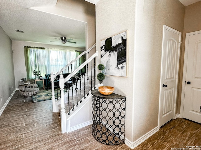 stairs featuring a textured ceiling and ceiling fan