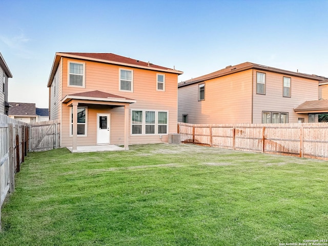 back of property with a yard and central AC unit