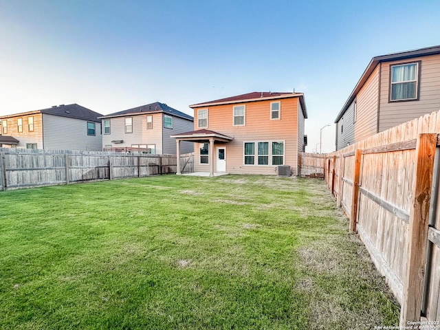 rear view of property with a yard and central AC unit