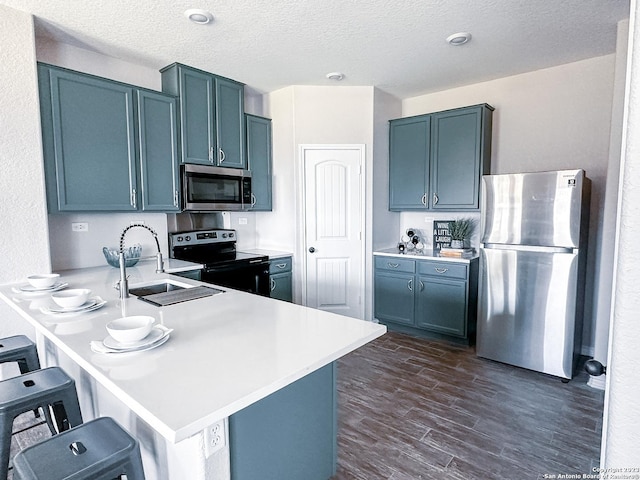 kitchen featuring dark wood-type flooring, a breakfast bar, sink, kitchen peninsula, and stainless steel appliances