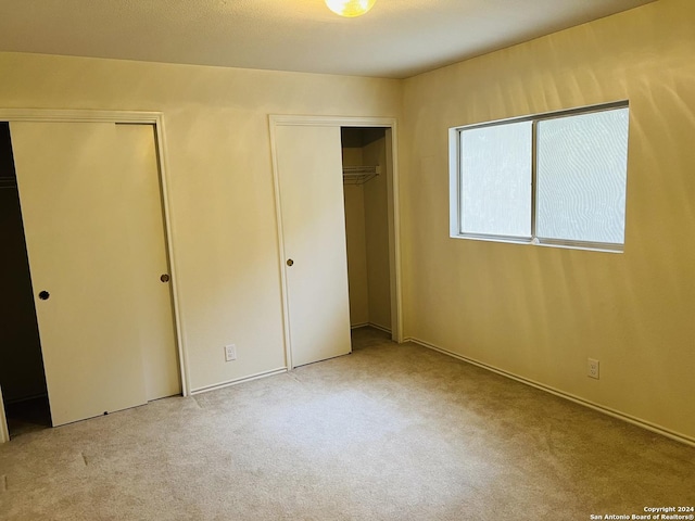 unfurnished bedroom featuring carpet flooring and two closets