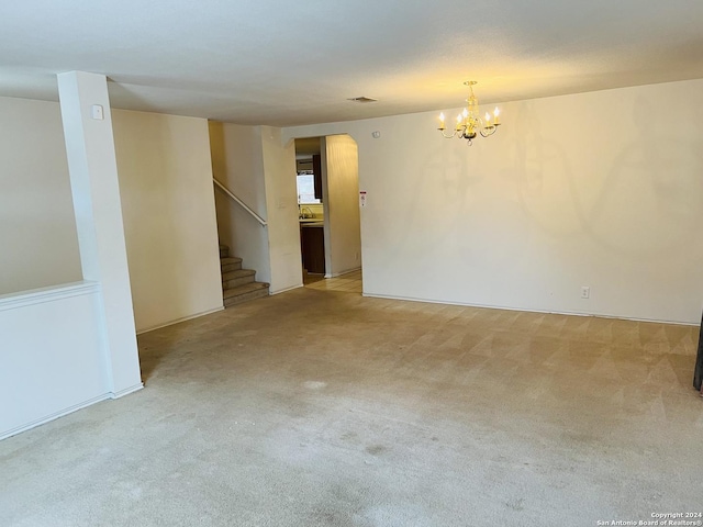 carpeted spare room featuring stairs, a sink, and a notable chandelier