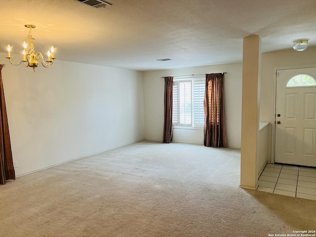 foyer featuring visible vents, light colored carpet, a notable chandelier, and a textured ceiling