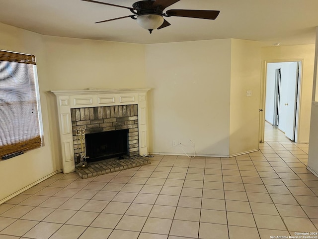 unfurnished living room with a brick fireplace, ceiling fan, and light tile patterned flooring