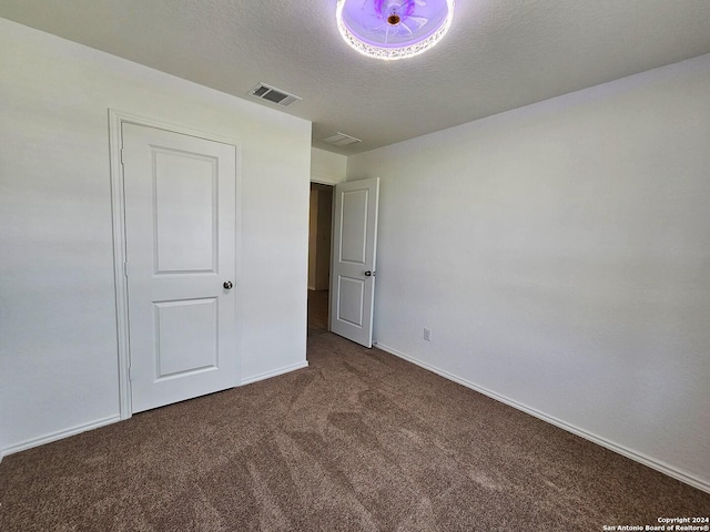 unfurnished bedroom featuring dark carpet and a textured ceiling