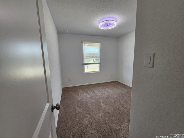 carpeted empty room featuring a textured ceiling