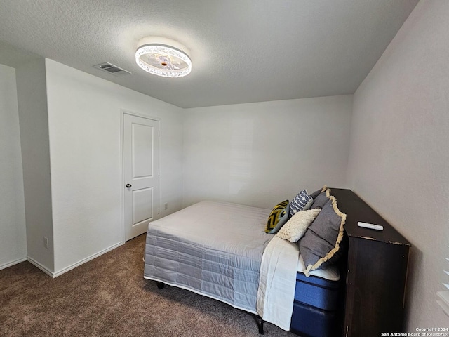 bedroom with dark carpet and a textured ceiling