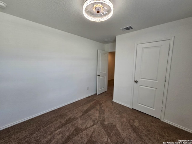 unfurnished bedroom with dark carpet and a textured ceiling