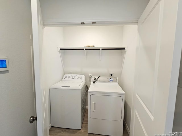 washroom with hardwood / wood-style floors and washing machine and clothes dryer