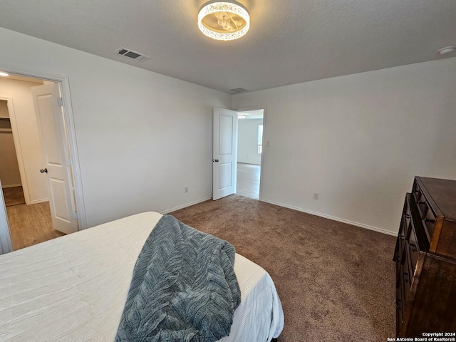 bedroom with a textured ceiling and dark colored carpet