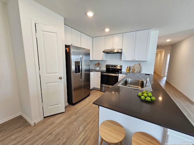 kitchen with light hardwood / wood-style floors, kitchen peninsula, sink, white cabinetry, and stainless steel appliances