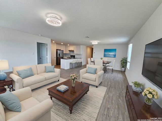 living room featuring light wood-type flooring and a textured ceiling