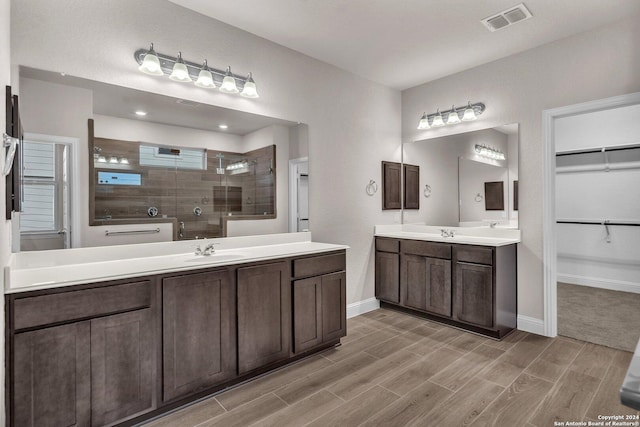 213 Fillmore Fls, Cibolo, TX 78108 - bathroom with tiled shower, two vanities, wood finished floors, and baseboards