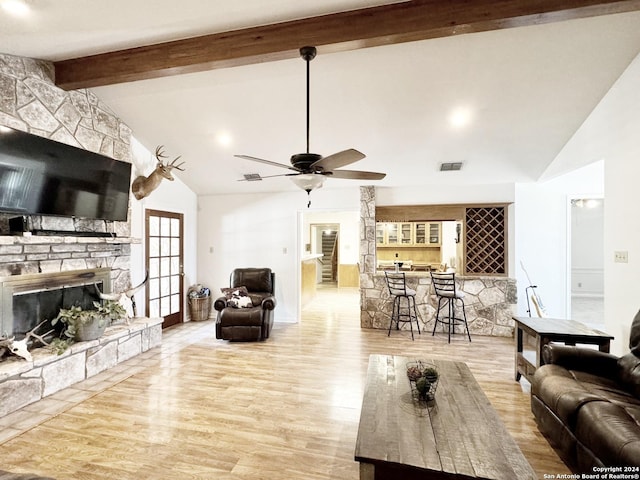 living room with light wood-type flooring, bar area, vaulted ceiling with beams, and a fireplace