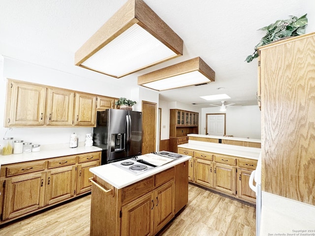 kitchen with a center island, stainless steel fridge, light hardwood / wood-style floors, a skylight, and white electric stovetop