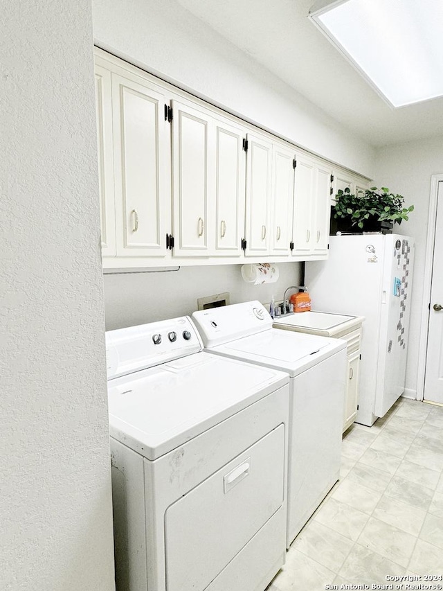 clothes washing area featuring cabinets and washer and clothes dryer