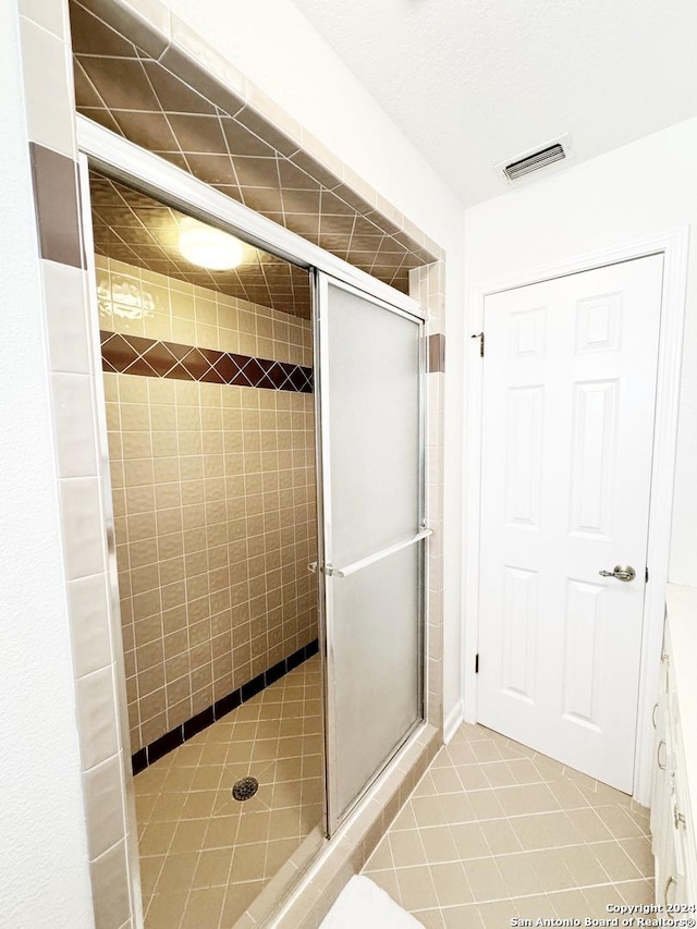 bathroom with walk in shower, tile patterned floors, and a textured ceiling