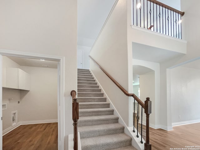 stairway featuring hardwood / wood-style flooring and a towering ceiling