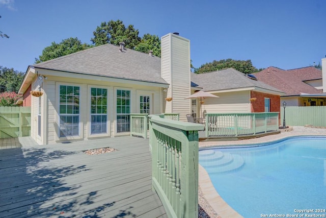 outdoor pool with fence and a wooden deck