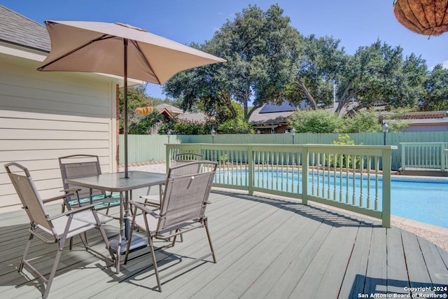 wooden deck featuring outdoor dining space, a fenced backyard, and a fenced in pool