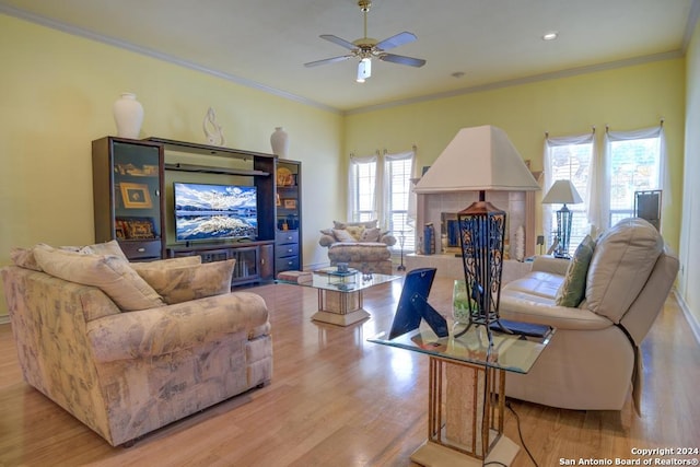 living room with a fireplace, light wood-type flooring, ceiling fan, and ornamental molding