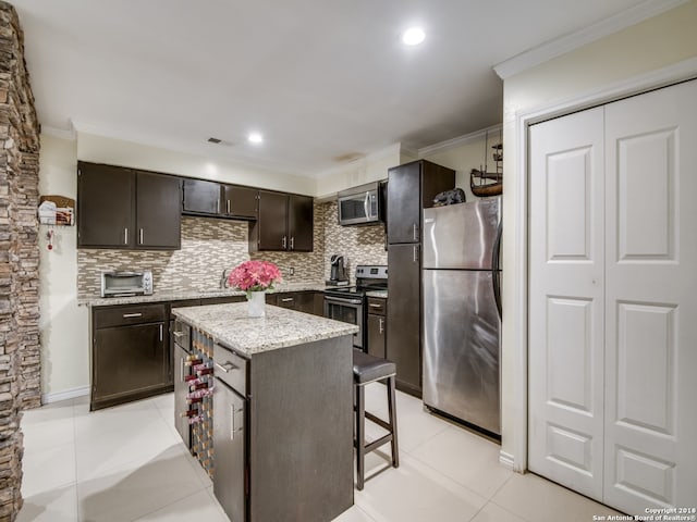 kitchen with backsplash, a center island, appliances with stainless steel finishes, and light tile patterned floors