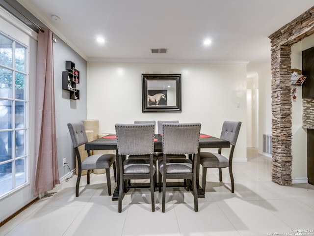 tiled dining room featuring ornate columns and crown molding