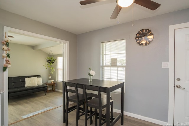 dining space featuring vaulted ceiling, wood finished floors, and baseboards