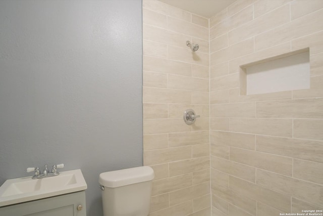 full bath featuring a tile shower, vanity, and toilet