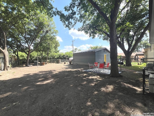 view of yard with fence, an outdoor structure, and a patio