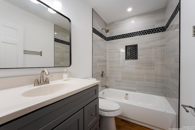 full bathroom with tiled shower / bath combo, vanity, hardwood / wood-style floors, and toilet