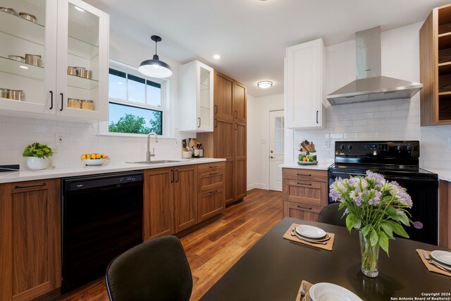 kitchen featuring black appliances, wall chimney range hood, sink, decorative backsplash, and dark hardwood / wood-style floors