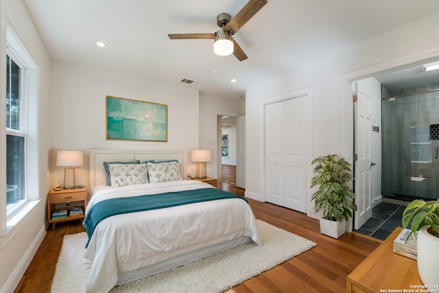 bedroom with ceiling fan, ensuite bath, and dark hardwood / wood-style floors