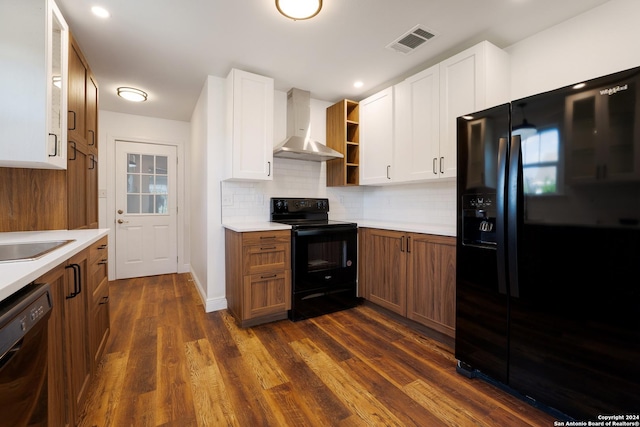 kitchen featuring dark wood-type flooring, black appliances, white cabinets, decorative backsplash, and wall chimney exhaust hood