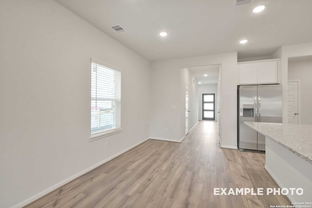 kitchen featuring light wood-type flooring, white cabinets, light stone countertops, and stainless steel fridge with ice dispenser