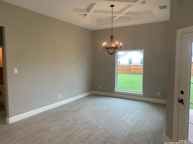 empty room with light wood-type flooring, beam ceiling, a notable chandelier, and coffered ceiling