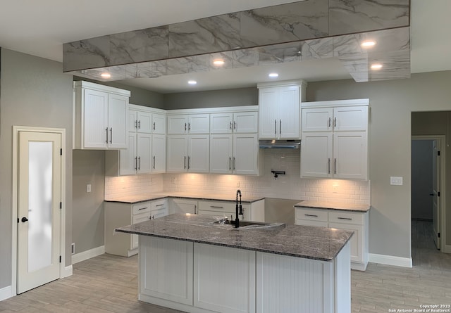 kitchen featuring sink, dark stone counters, white cabinets, and backsplash