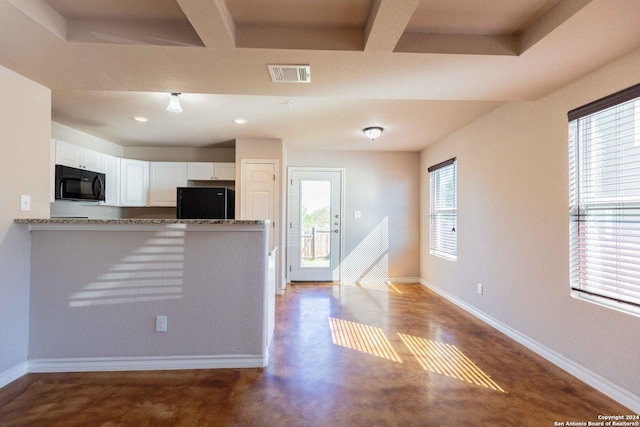 kitchen featuring light stone countertops, kitchen peninsula, concrete floors, white cabinets, and black appliances