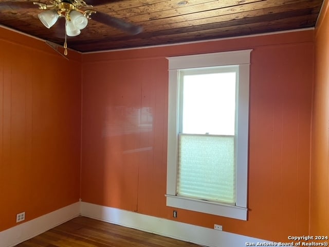 empty room with ceiling fan, hardwood / wood-style floors, and wooden ceiling