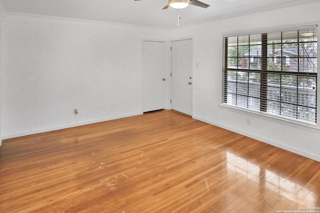 empty room featuring crown molding, light wood-type flooring, and ceiling fan