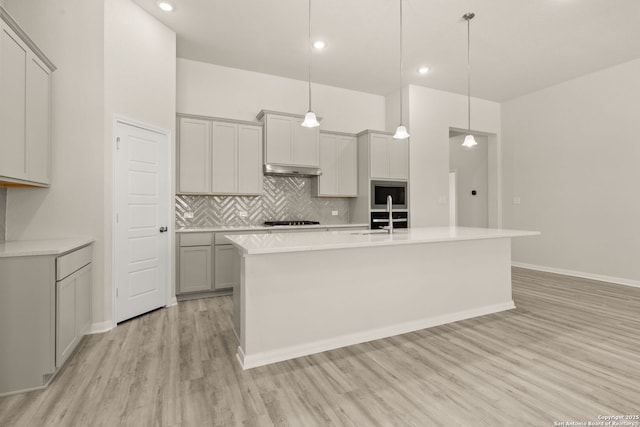 kitchen featuring pendant lighting, gray cabinets, and a center island with sink