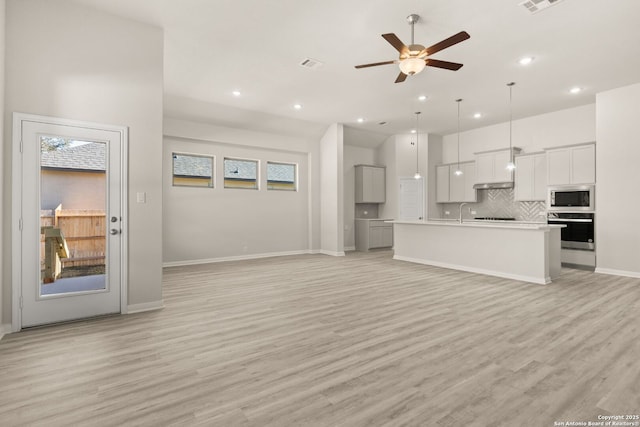 unfurnished living room featuring ceiling fan, sink, and light wood-type flooring